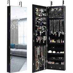 an open mirrored cabinet with jewelry hanging from it's sides and a couch in the background