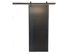 a tall black door hanging from the side of a white wall with an iron bar on it