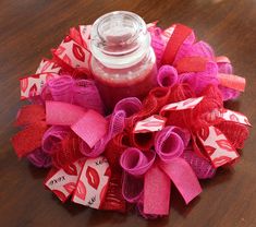 a pink and red hair bow sitting on top of a wooden table next to a jar