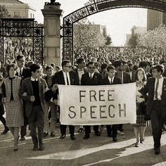 a group of people walking down a street holding a free speech sign