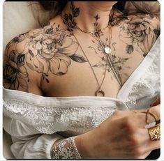 a woman with tattoos on her chest is holding a ring and wearing a white dress