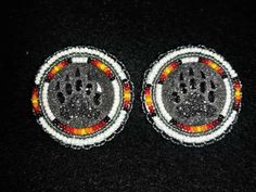 two black and white buttons with red, yellow and orange designs on them sitting on a black surface