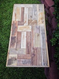 a wooden table sitting on top of a lush green grass covered park area next to a brick walkway