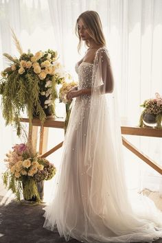 a woman in a wedding dress standing next to flowers