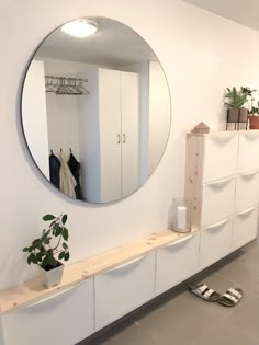 a mirror is hanging on the wall above a shelf with a potted plant next to it