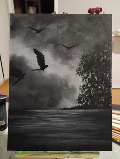 a black and white painting of two birds flying over the water with trees in the background