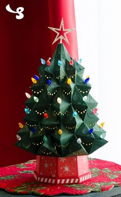 an origami christmas tree in a red box on a table with a star