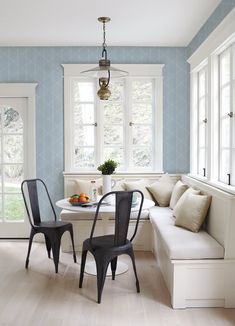 a dining room with blue walls and white furniture in the corner, along with two black chairs