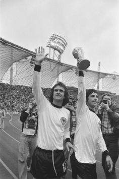 two men are holding up their trophies in front of an audience at a sporting event