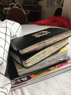 a stack of books sitting on top of a bed