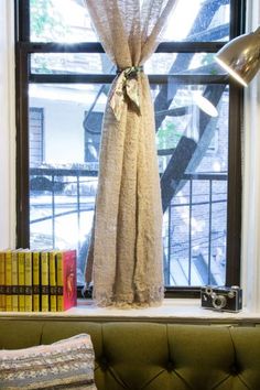 a window sill in front of a book shelf with books and a lamp on it