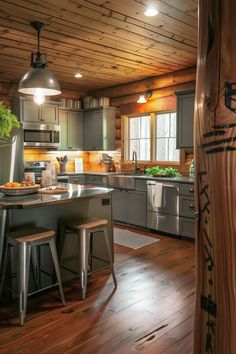 a large kitchen with wooden floors and gray cabinetry, along with two stools