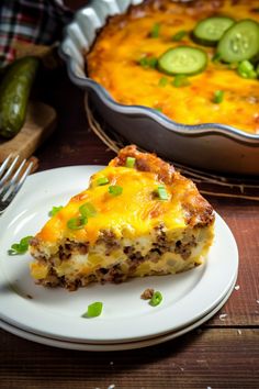 a slice of quiche on a plate next to a casserole dish with cucumbers