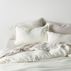 an unmade bed with white sheets and pillows