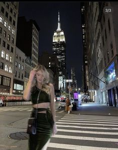 a woman is walking down the street in new york city at night with her hand on her head