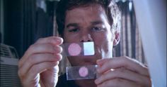 a man holding up a piece of glass to his face with dots on it in front of him