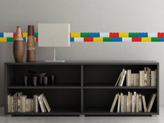 a shelf with books and vases on top of it in front of a wall