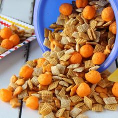 a blue bowl filled with cheetos next to a yellow and white paper plate