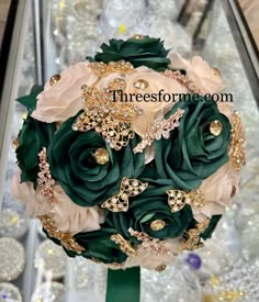 a bridal bouquet with green roses and gold brooches on display in a store