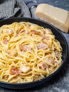 chicken and bacon pasta in a skillet next to some bread on the side with text overlay