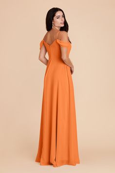 a woman in an orange dress with her back to the camera, looking off into the distance