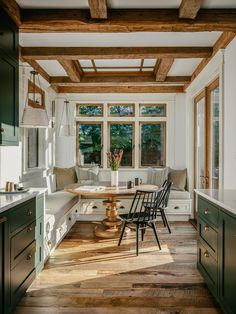 a kitchen with green cabinets and wooden floors, along with a table in the center