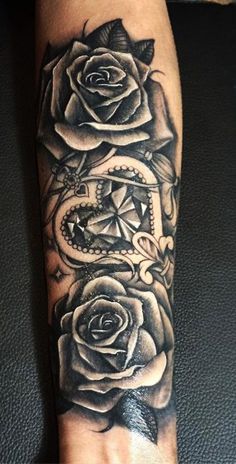 a black and white tattoo with roses on the arm, in front of a woman's hand