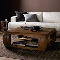 a coffee table sitting on top of a rug in front of a white couch next to a book shelf