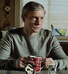 a man sitting at a table holding a cup