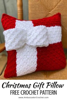 a red and white crocheted pillow with a bow on it's side