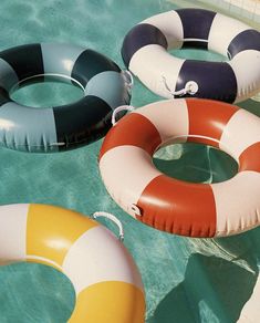 four inflatable floats floating on the water next to a swimming pool with no people