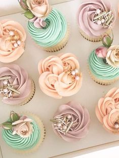 cupcakes decorated with pastel colors and flowers on a white tray, ready to be eaten