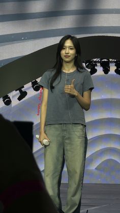 a woman standing in front of a stage with headphones on her ears and holding a cell phone