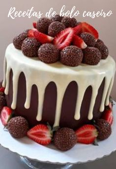 a chocolate cake topped with strawberries and drizzled in white icing