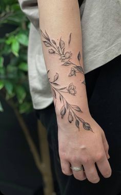 a woman's arm with flowers and leaves tattooed on the left side of her wrist