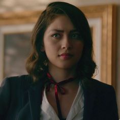 a woman wearing a black jacket and red bow tie standing in front of a mirror