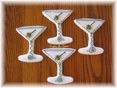 four decorated cookies in the shape of martini glasses on a wooden table with text overlay that says sugar & spice