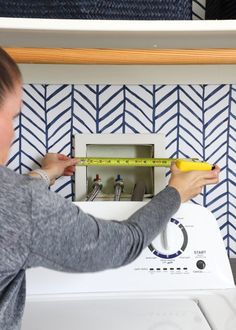 a woman is measuring the wall with a tape