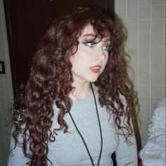 a woman with long red curly hair in a bathroom