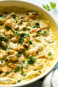 a casserole dish filled with chicken, cheese and parsley in a cream sauce