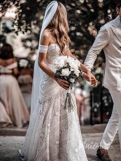 a bride and groom walking down the street holding hands in their wedding day attire,