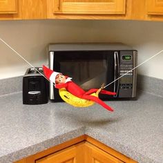 an elf is hanging from the side of a microwave