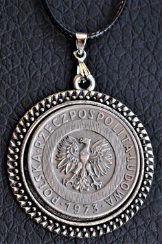 Large Poland White Eagle Coat of Arms Coin Pendant made from a 1973 20 Zlotych.  Coin size is apx. that of a US Half Dollar and is mounted in a Decorative Cabochon Tray attached with Pinch Bail and 20 Inch Black Nylon Cord Chain with Lobster Clasp.  There's a high polish and coin is in great condition.   IssuerPoland  PeriodPeople's Republic (1952-1989) TypeStandard circulation coin Years1973-1976 Value20 Złotych (20 PLZ) CurrencyThird złoty (1949-1994) CompositionCopper-nickel Weight10.15 g Diameter29 mm Thickness1.95 mm White Eagle, Coin Pendant Necklace, Men Jewelry, Half Dollar, Coin Pendant, Black Nylons, Coat Of Arms, Lobster Clasp, Poland