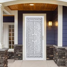 a white door is in front of a blue house with stone pillars and columns on either side