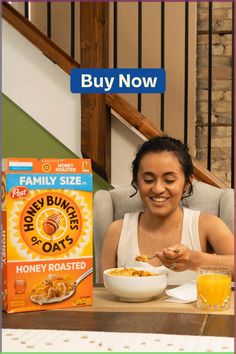 a woman sitting at a table with cereal and orange juice in front of her face