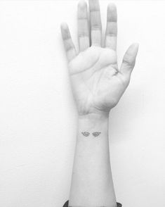 a person's hand with a small butterfly tattoo on the middle of their wrist