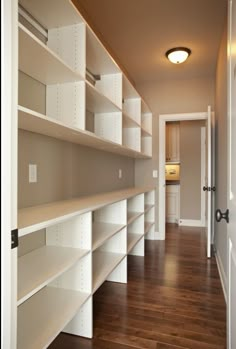 empty white shelves in the middle of a room with wooden floors and hard wood flooring