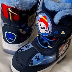 a child's shoe with paw patrol on the side and blue fur lined inside