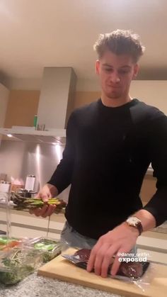 a man standing in front of a counter cutting up food on top of a wooden board