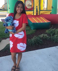 a woman holding a stuffed animal in front of a bouncy house